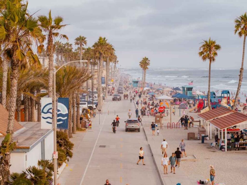 Palm-lined beachfront promenade with people walking along the Southern California coast