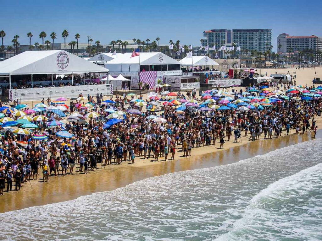 Large crowd and event tents on the sand for a surfing competition at Huntington Beach
